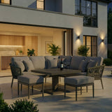 Grey outdoor corner sofa set with coffee table and footstools on a modern patio at dusk