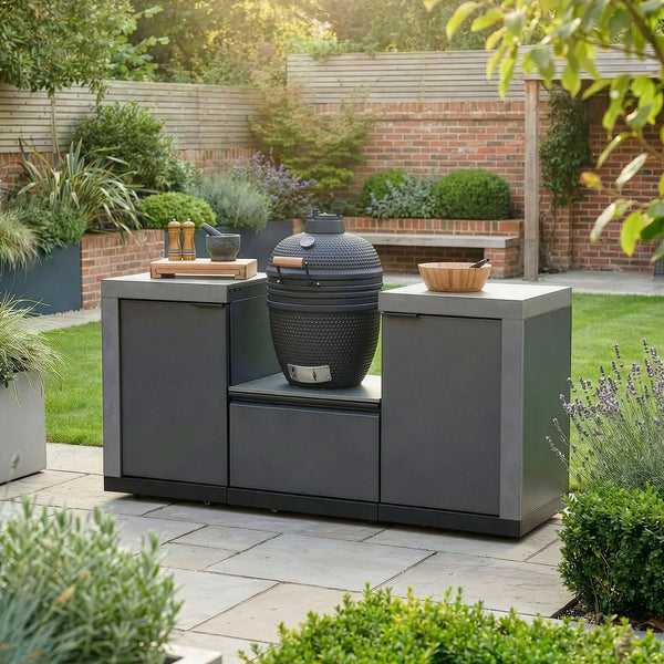 Outdoor kitchen with charcoal barbecue grill and cabinets on a patio in a landscaped garden
