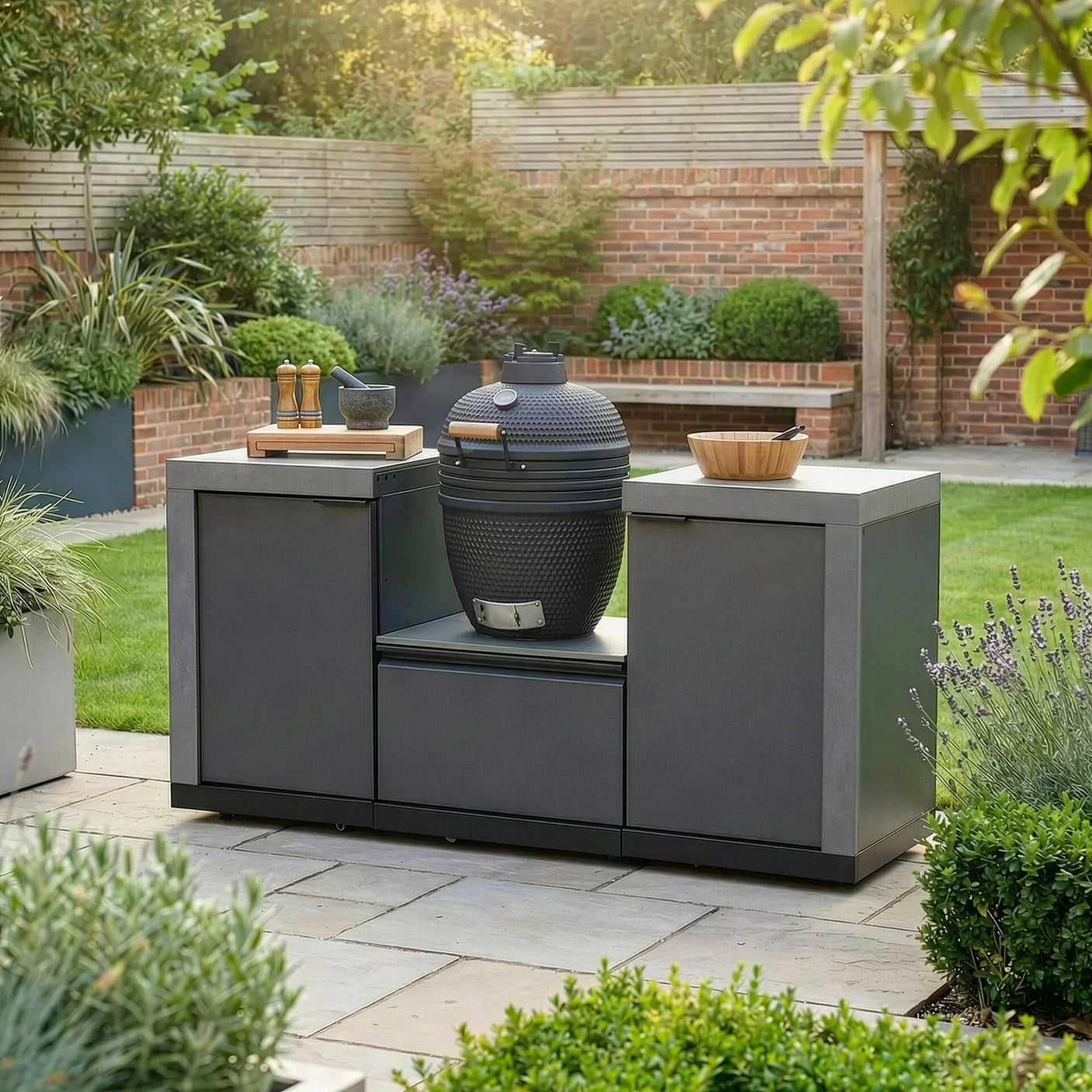 Outdoor kitchen with charcoal barbecue grill and cabinets on a patio in a landscaped garden