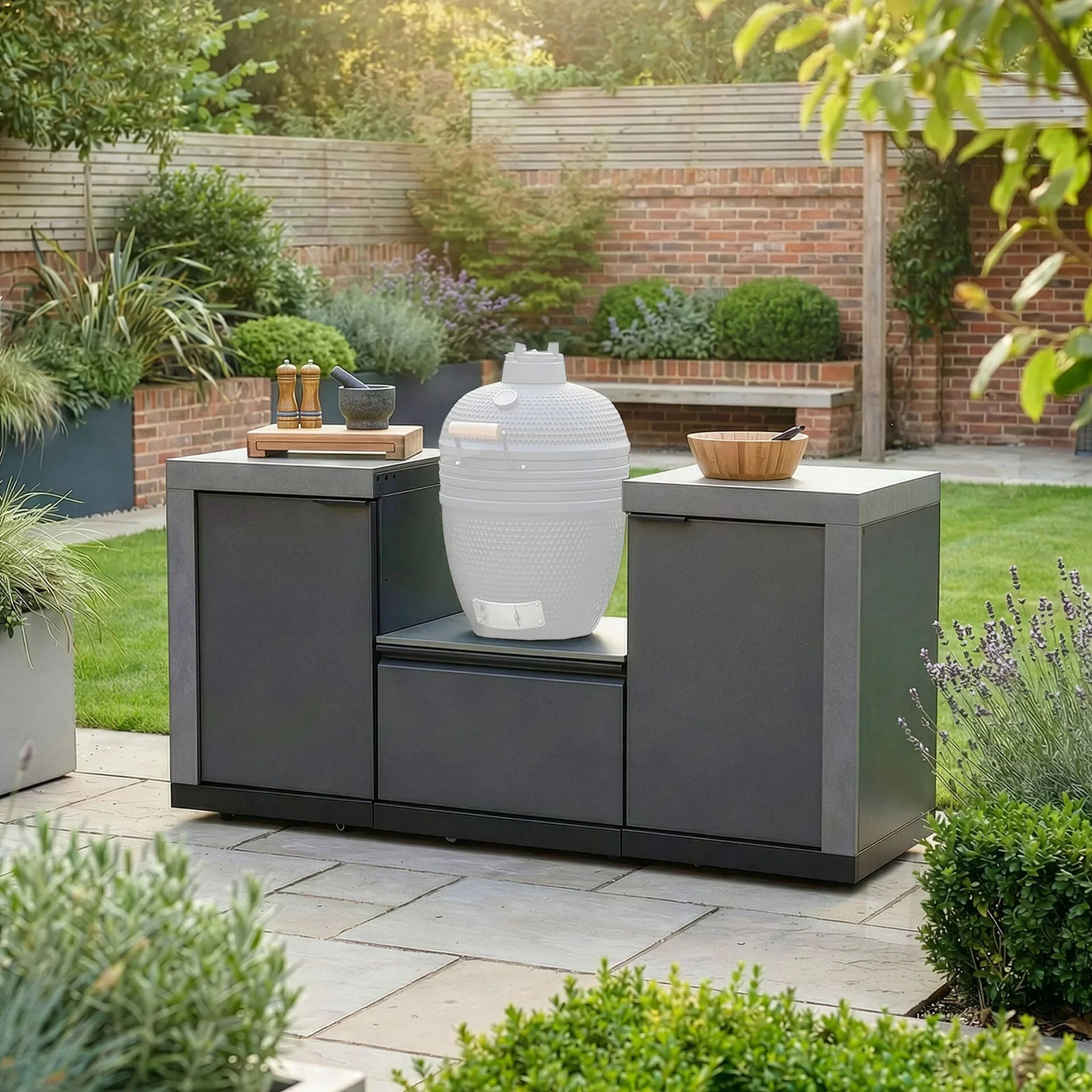 Modern outdoor kitchen unit with ceramic barbecue grill and accessories in garden setting