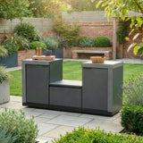 Outdoor kitchen unit with grey cabinets and stone countertops on a garden patio