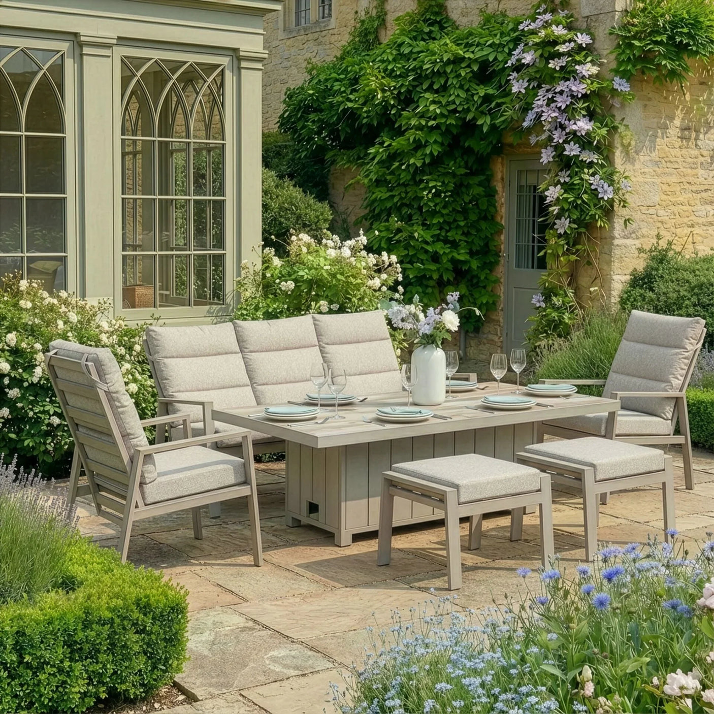 Beige cushioned outdoor dining set with table and chairs on patio surrounded by garden plants