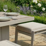 Modern garden dining table set with cushioned bench and plates on patio