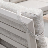 Closeup of outdoor sofa cushion with beige woven fabric and strap on slatted metal frame