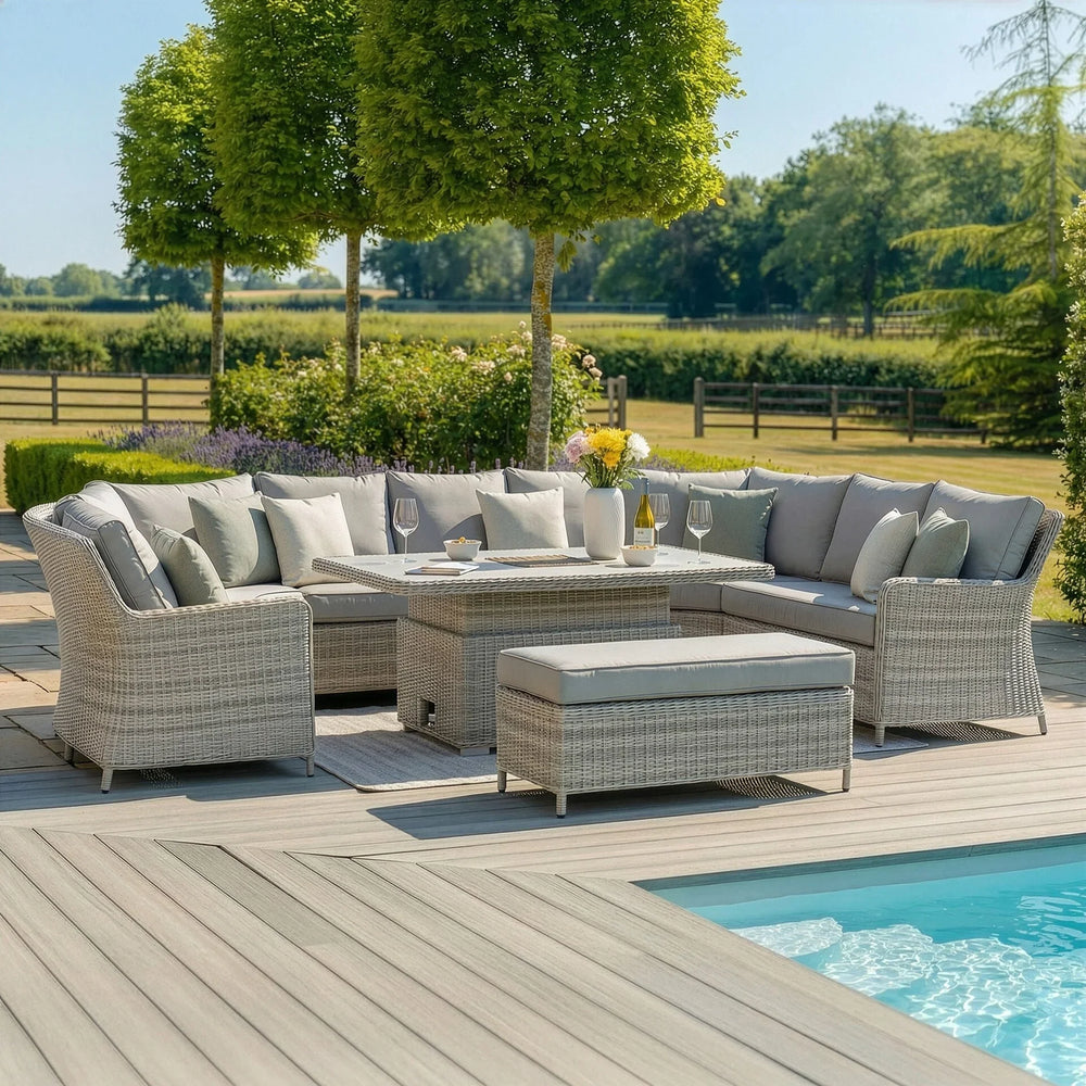 Grey rattan garden corner sofa set with cushions and glass-top dining table by a pool