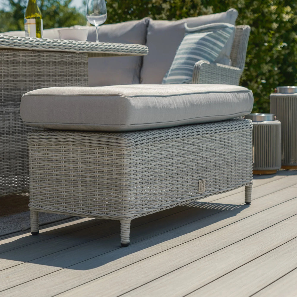 Light grey rattan outdoor footstool with cushion on patio decking