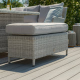 Light grey rattan outdoor footstool with cushion on patio decking