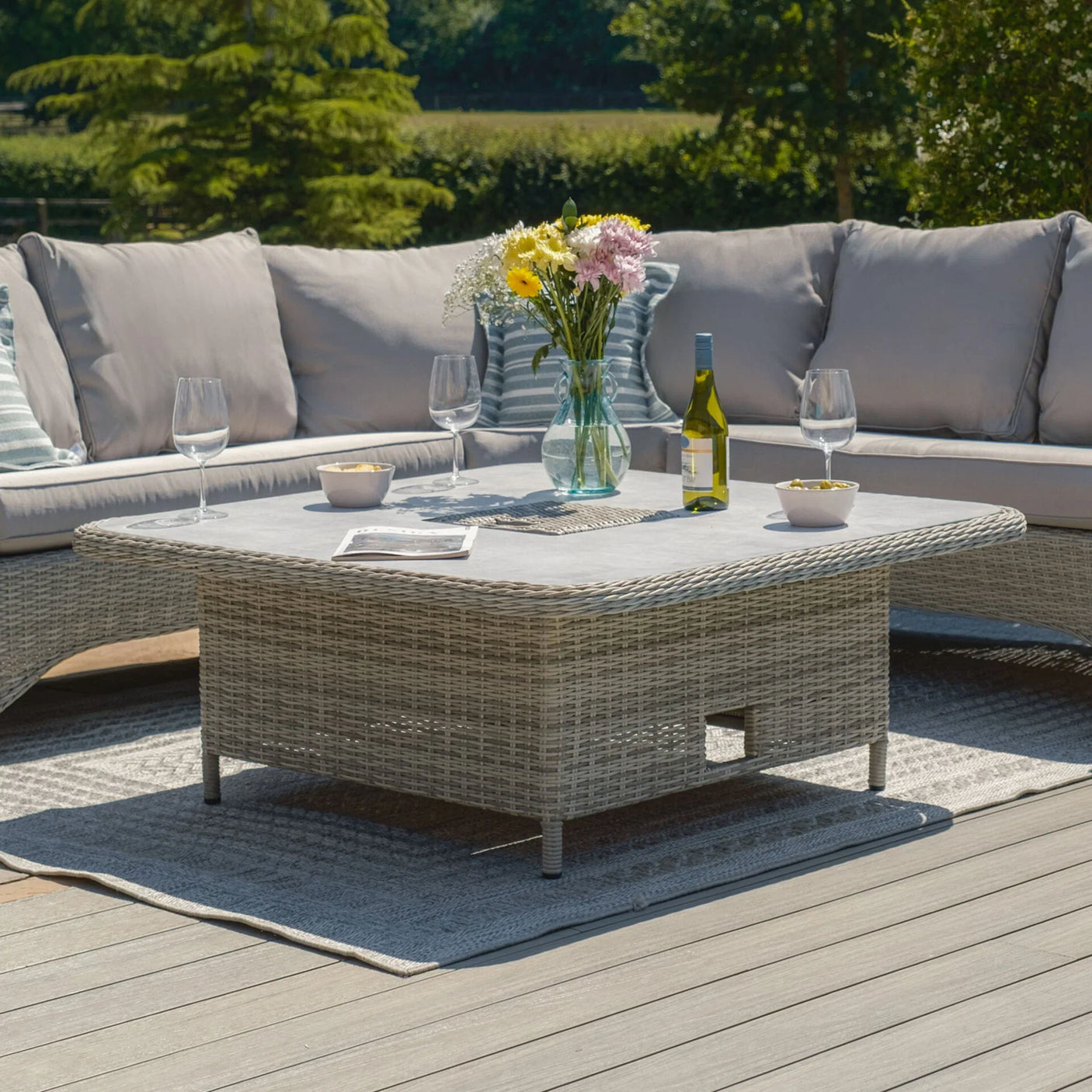 Rattan outdoor corner sofa set with grey cushions and matching dining table on patio