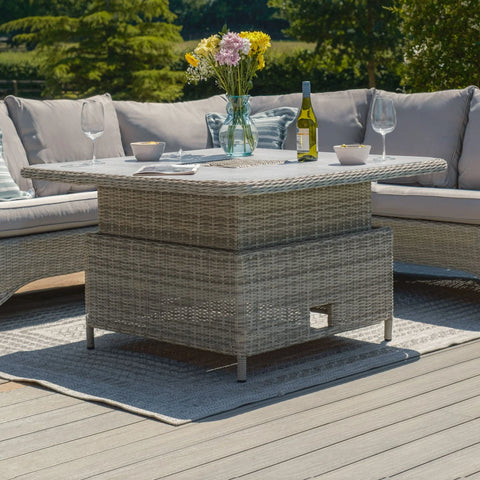 Grey rattan garden corner sofa with glass top table, wine, flowers, and outdoor rug