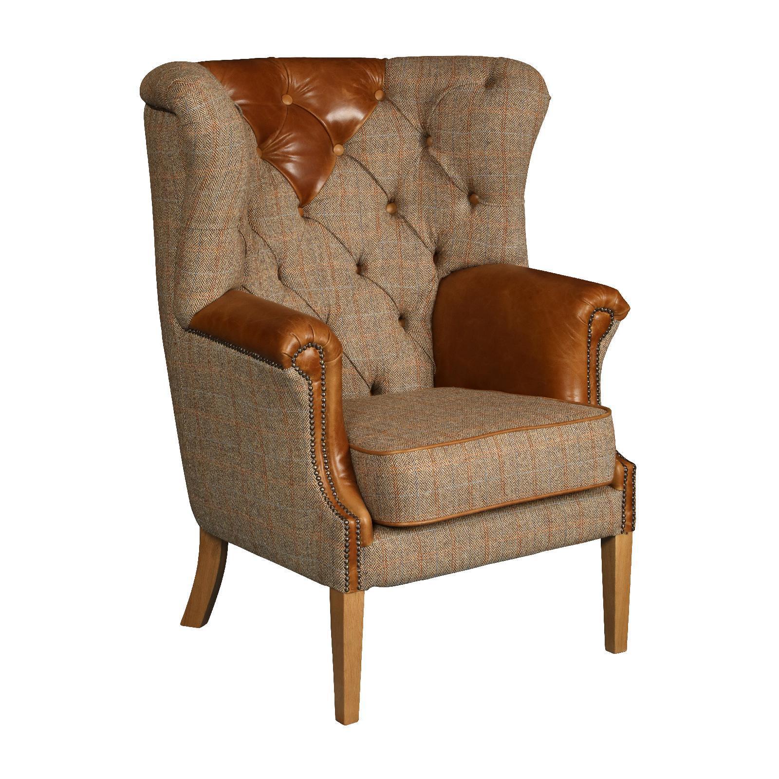 Wingback armchair with tan leather and tweed upholstery, studded trim, and wooden legs