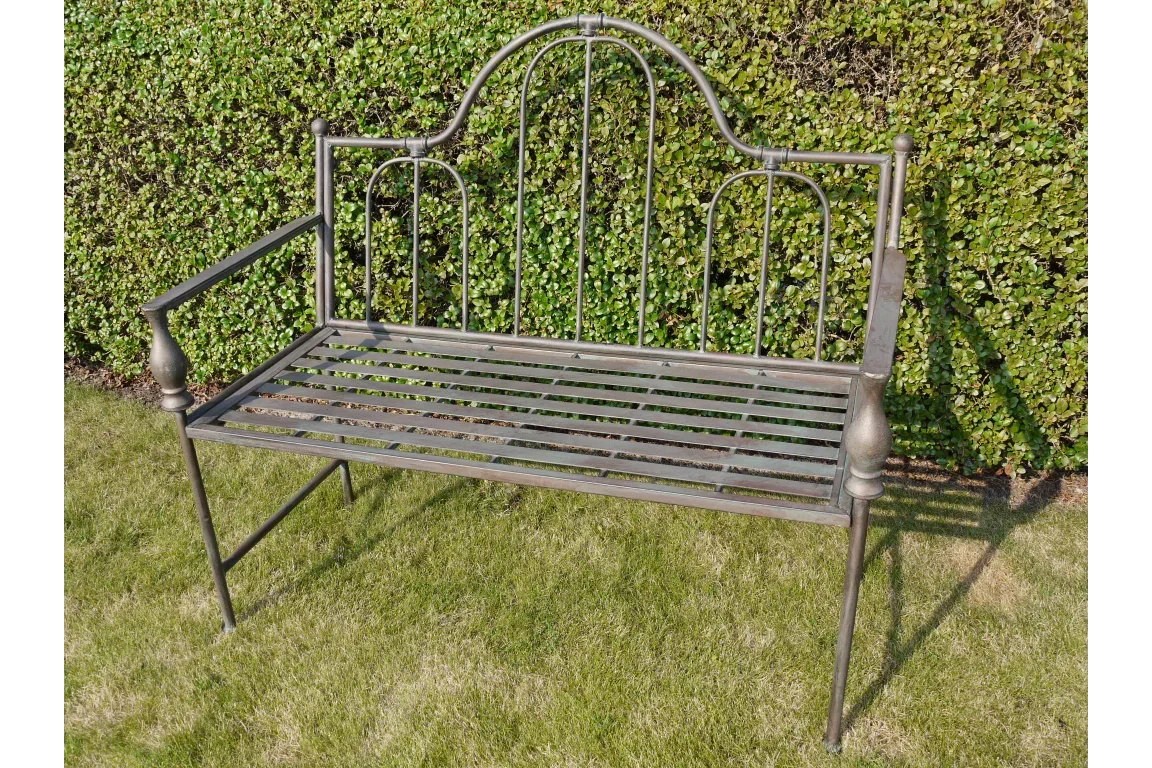 Black metal garden bench with arched backrest and slatted seat on lawn