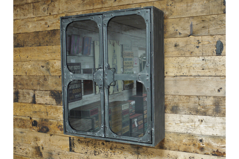 Metal wall cabinet with glass double doors, rivet details, mounted on rustic wooden plank wall, angled view.