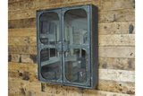 Metal wall cabinet with glass double doors, rivet details, mounted on rustic wooden plank wall, angled view.