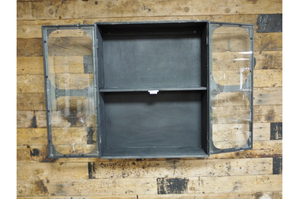 Black metal wall cabinet with two glass paneled doors open, showing one shelf, mounted on wood wall