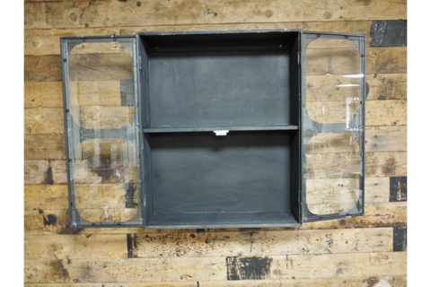 Black metal wall cabinet with two glass paneled doors open, showing one shelf, mounted on wood wall