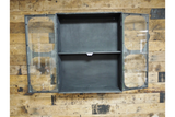 Black metal wall cabinet with two glass paneled doors open, showing one shelf, mounted on wood wall