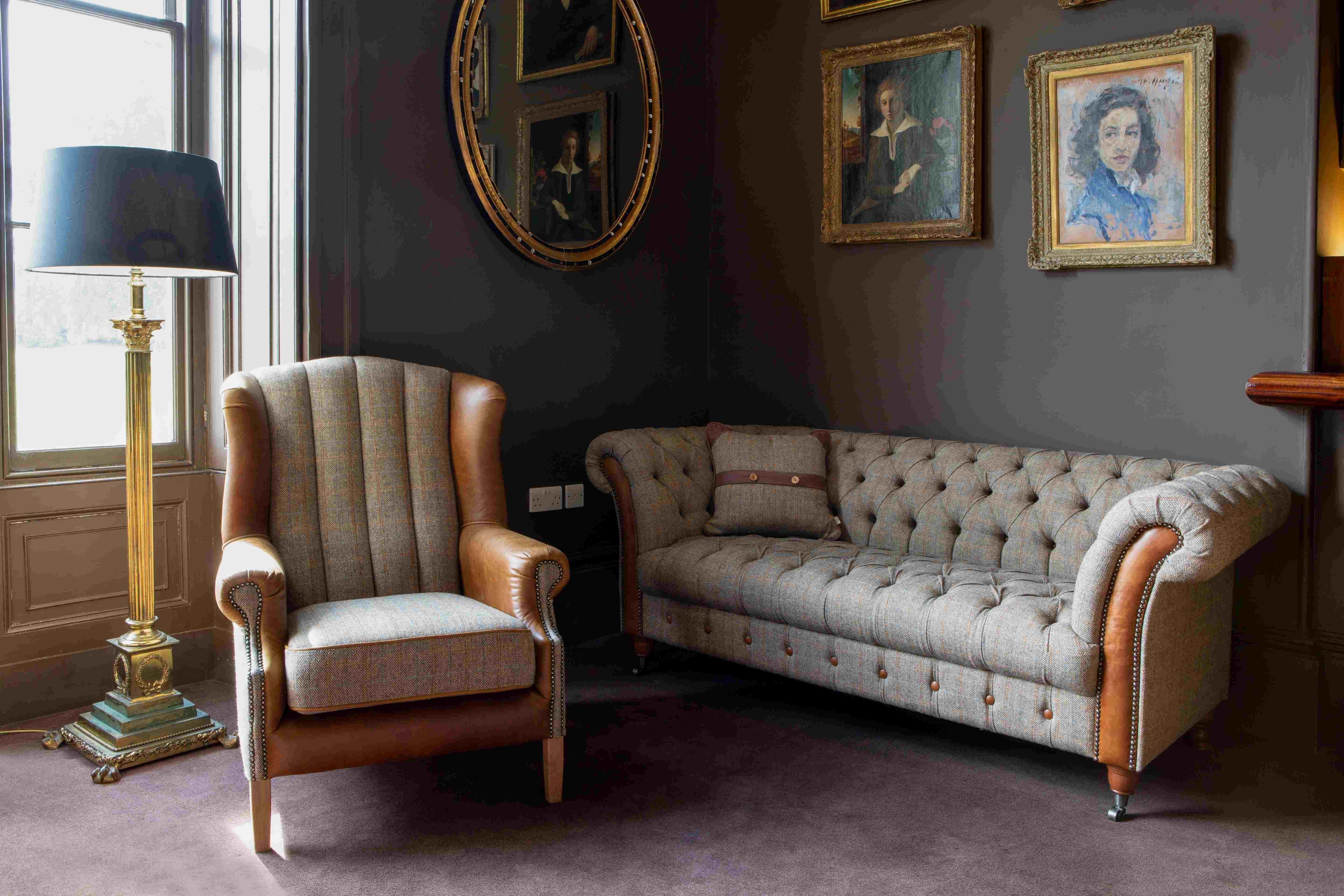 Tufted grey fabric sofa and wingback armchair with leather accents in a living room