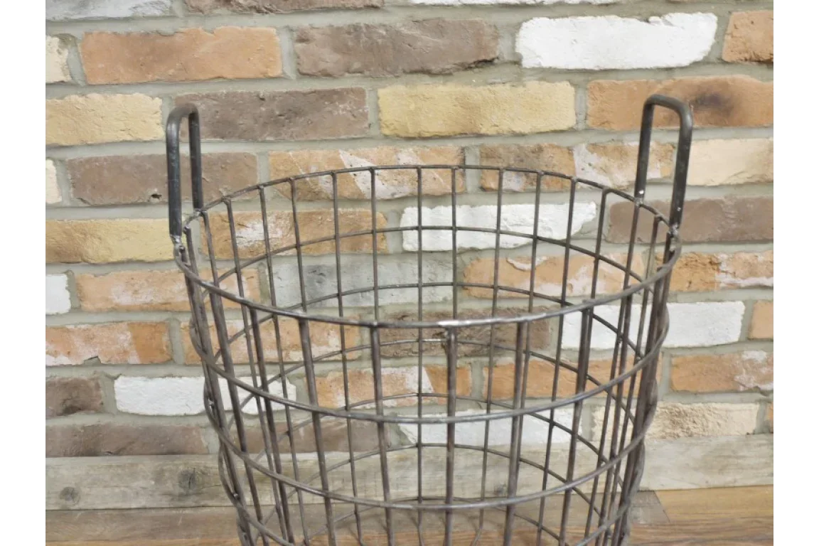 metal wire storage basket with handles against brick wall