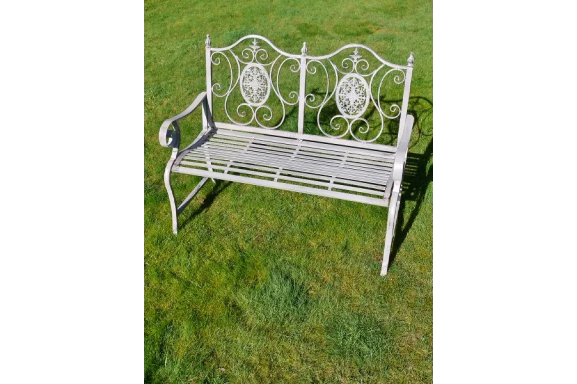 Decorative metal garden bench with ornate backrest design on grass lawn