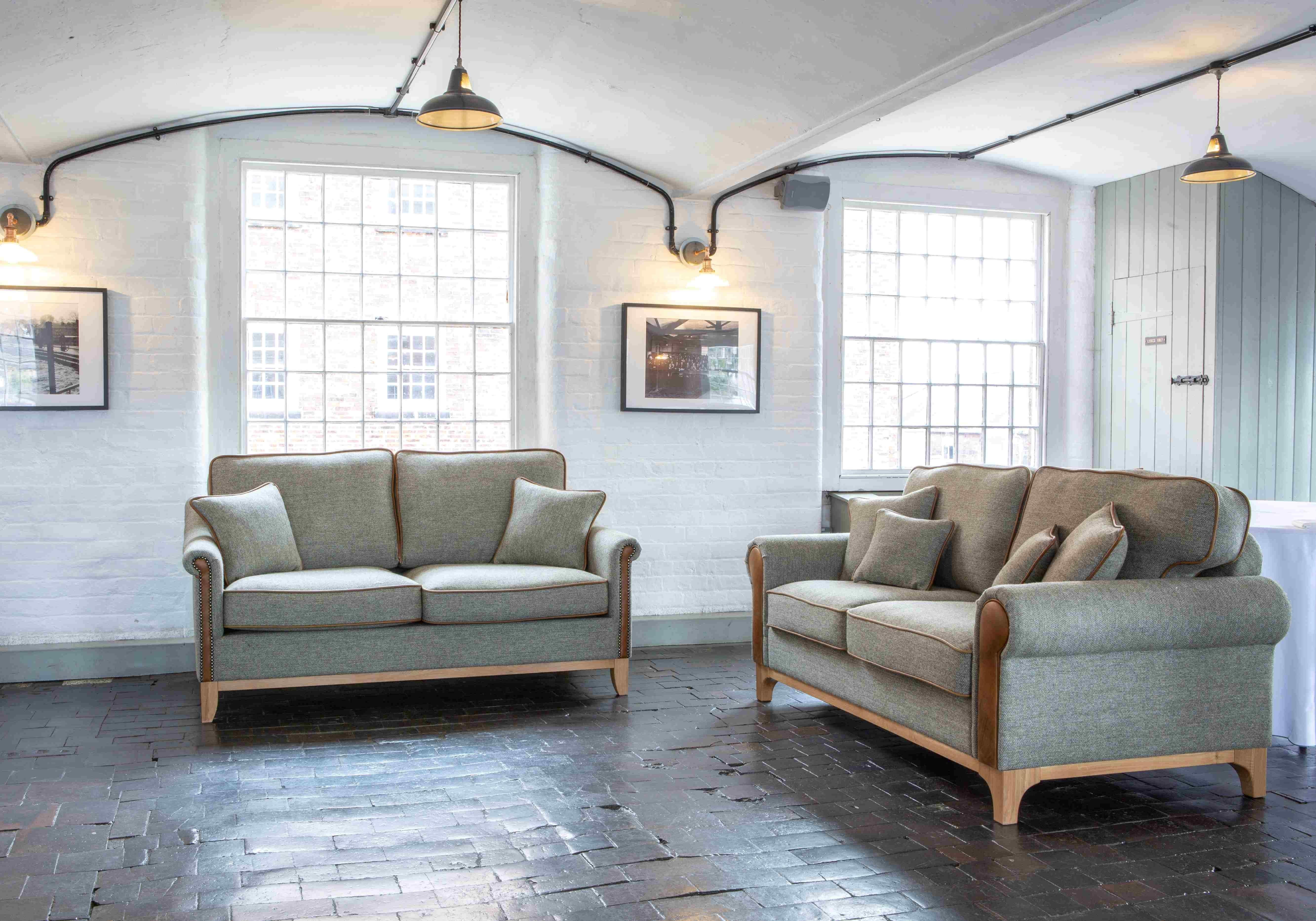 Modern grey fabric sofas with wooden legs in bright living room with large windows