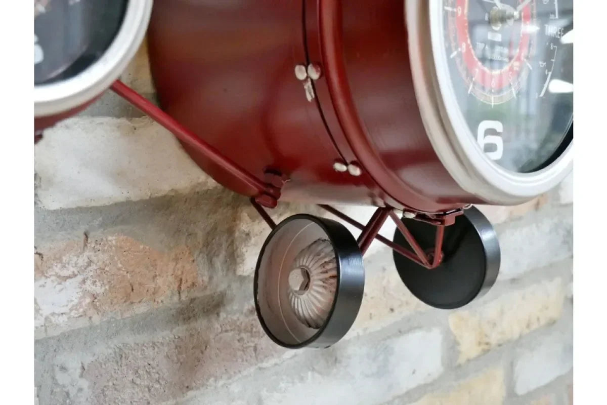 Red metal airplane wall clock close up showing wheels and round clock face detail