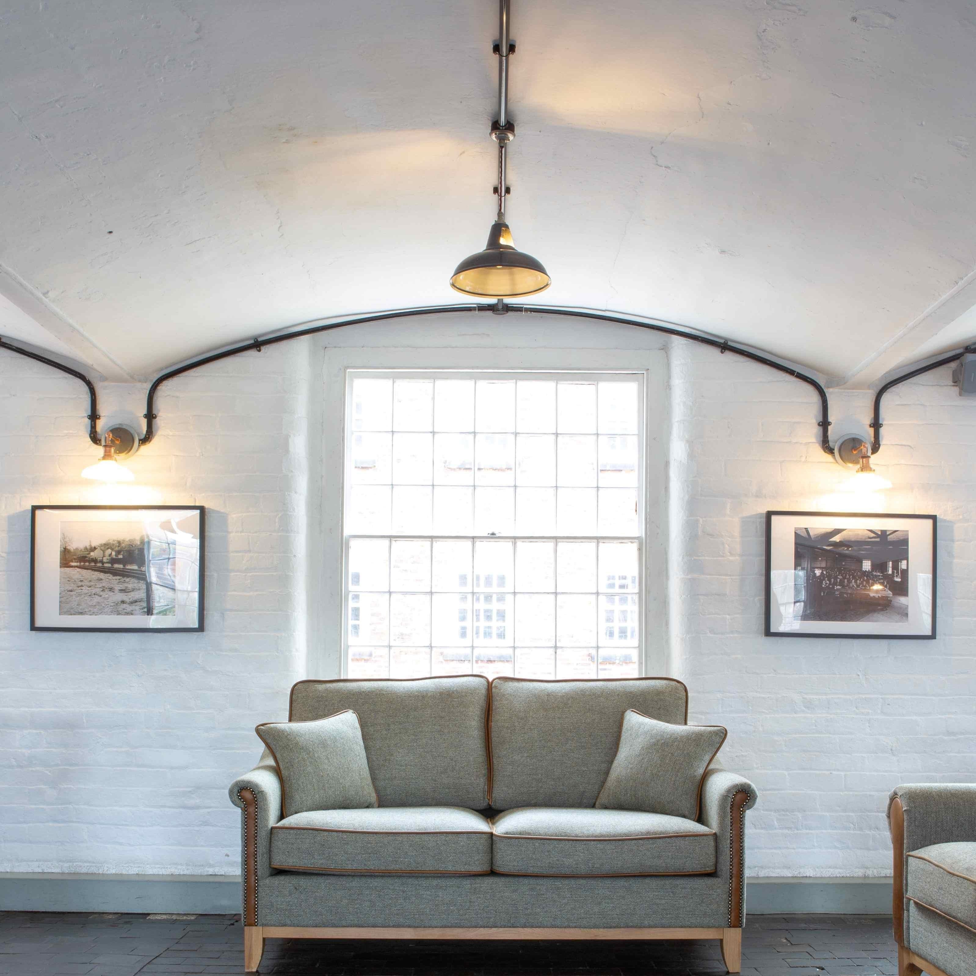 Grey fabric sofa with wooden legs in front of window, brick wall, and framed photos