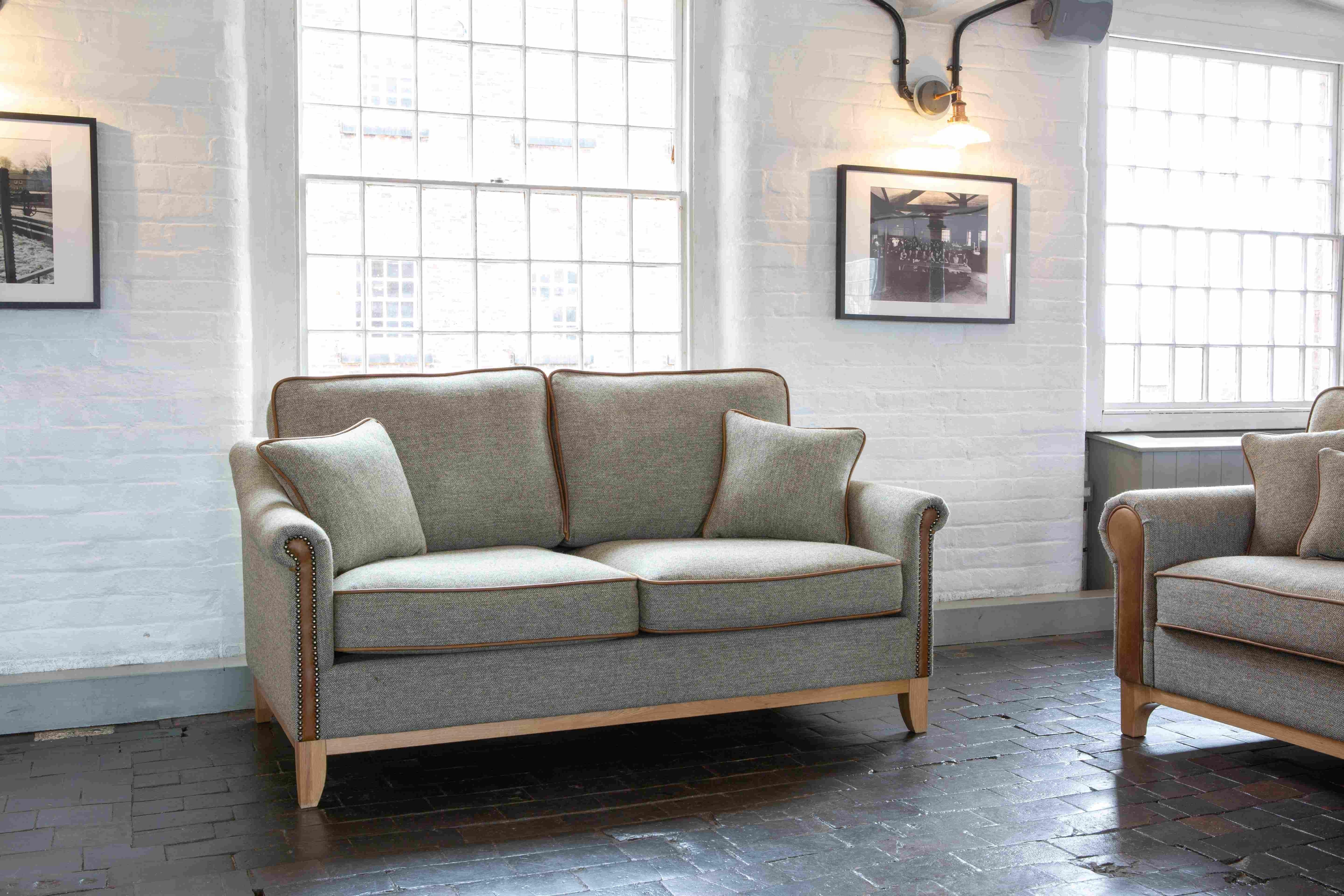Grey fabric sofa with wooden base and studded arms in modern living room