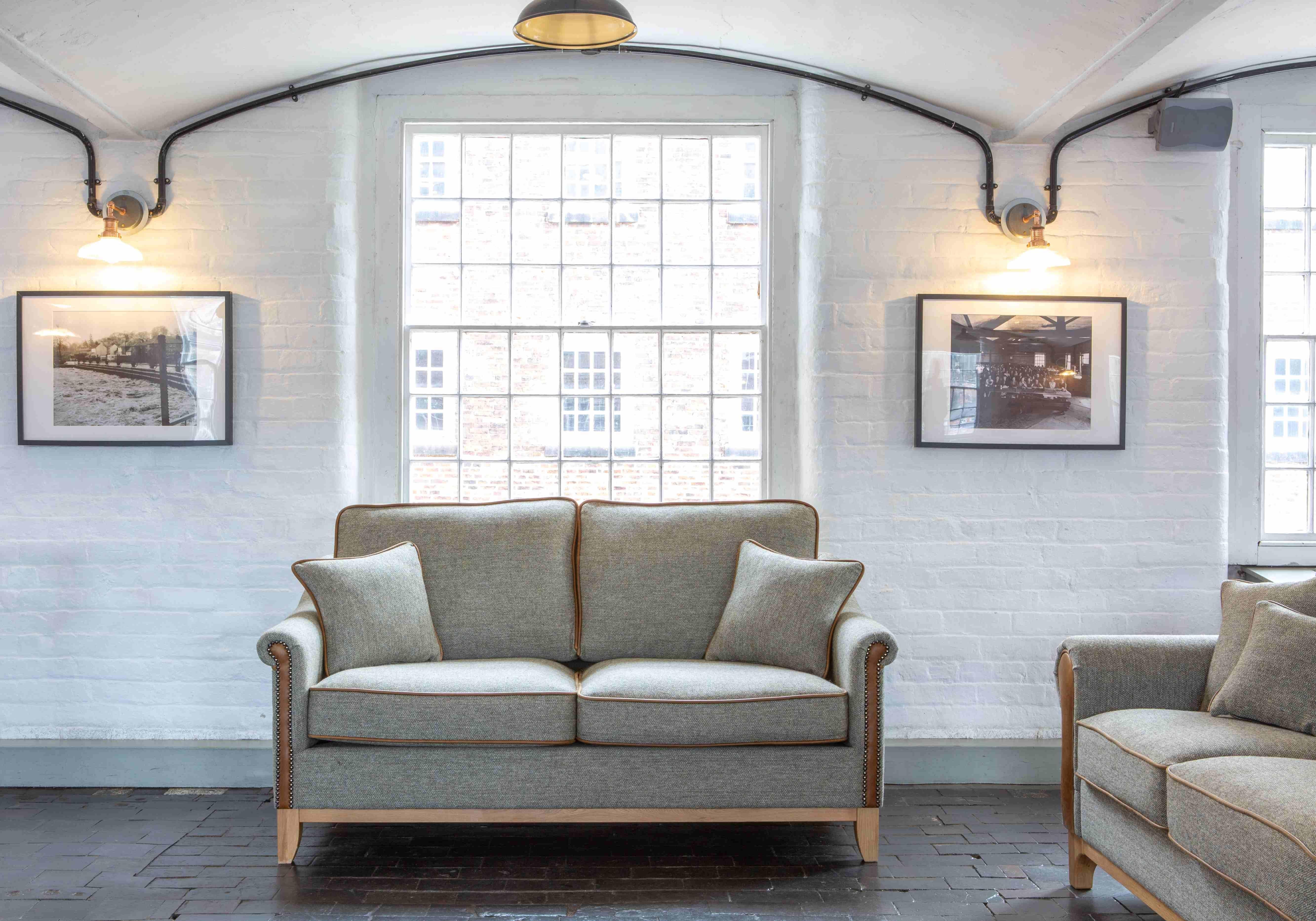 Grey fabric sofa with wooden legs and stud detailing in a bright living room