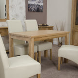 Oak dining table with cream leather chairs in a modern dining room setting