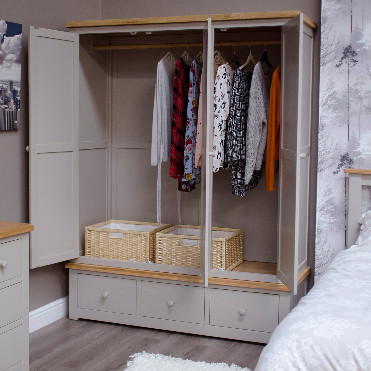 Grey wooden wardrobe with hanging rail, baskets and closed drawers in bedroom setting