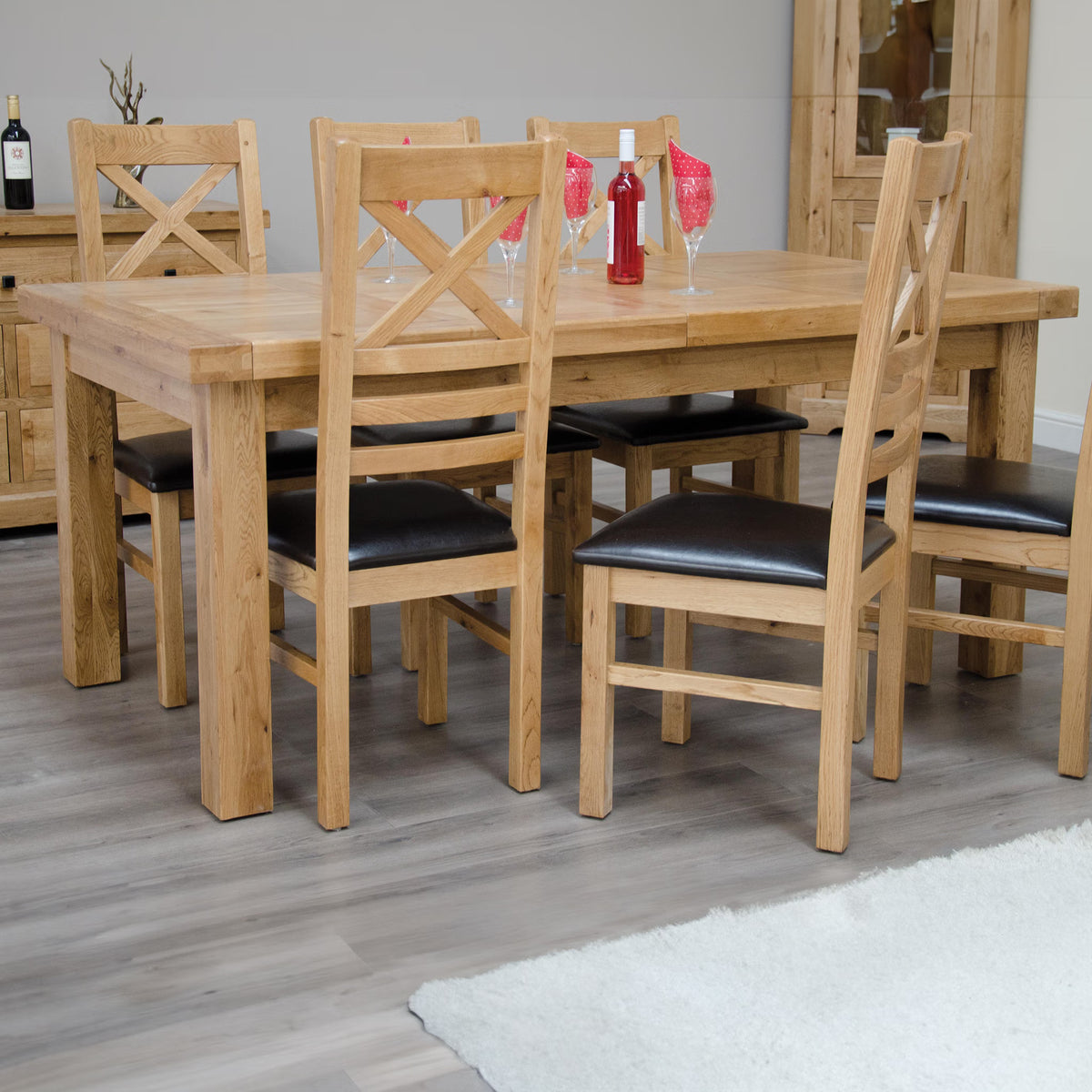 Oak dining table set with six chairs, black seat pads, set on grey wood flooring