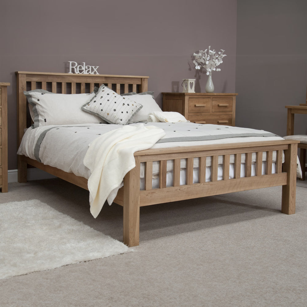 Oak bed frame with slatted headboard, neutral bedding and wooden bedside cabinet