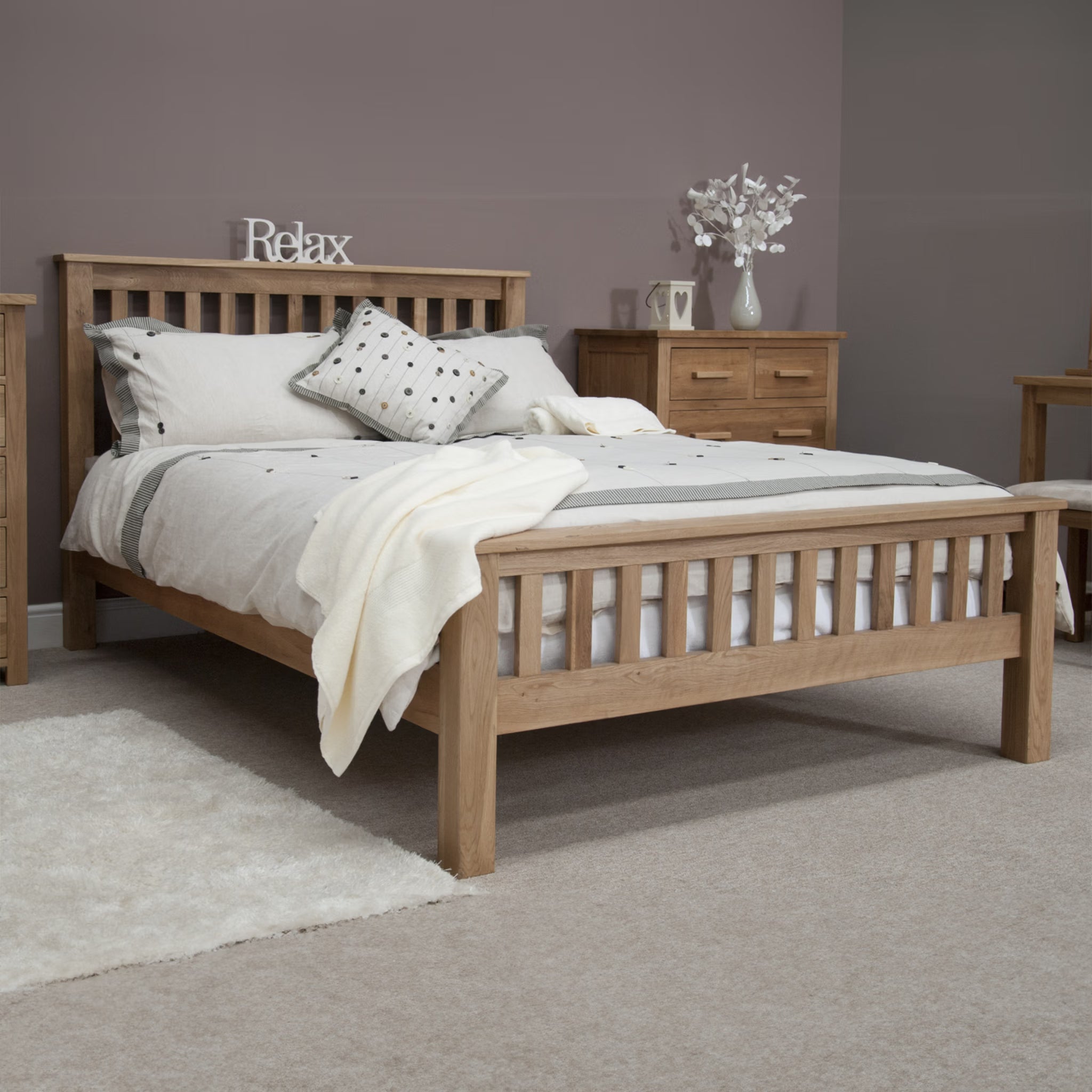 Oak bed frame with slatted headboard, neutral bedding and wooden bedside cabinet