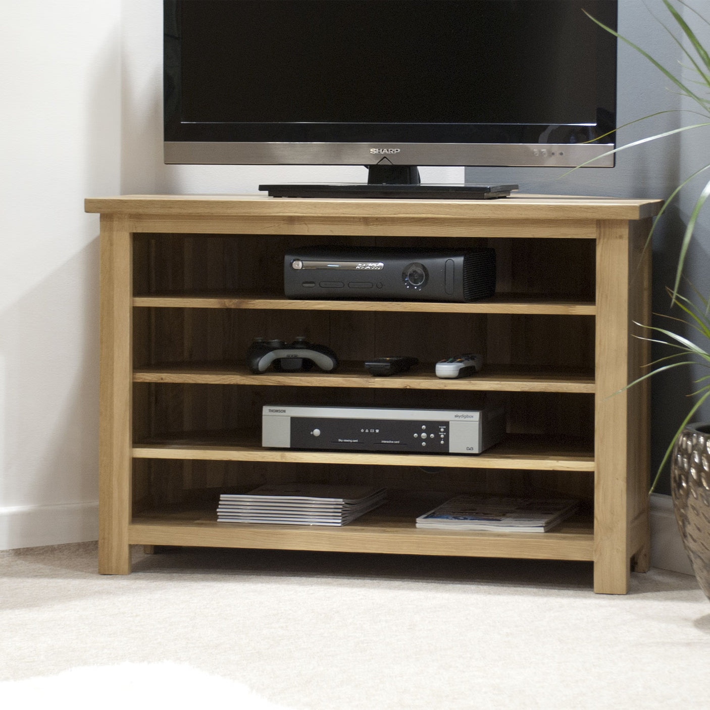 Oak TV unit with open shelves, holding electronics and game controllers in living room corner