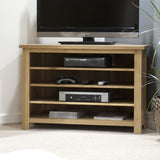 Oak TV unit with open shelves, holding electronics and game controllers in living room corner
