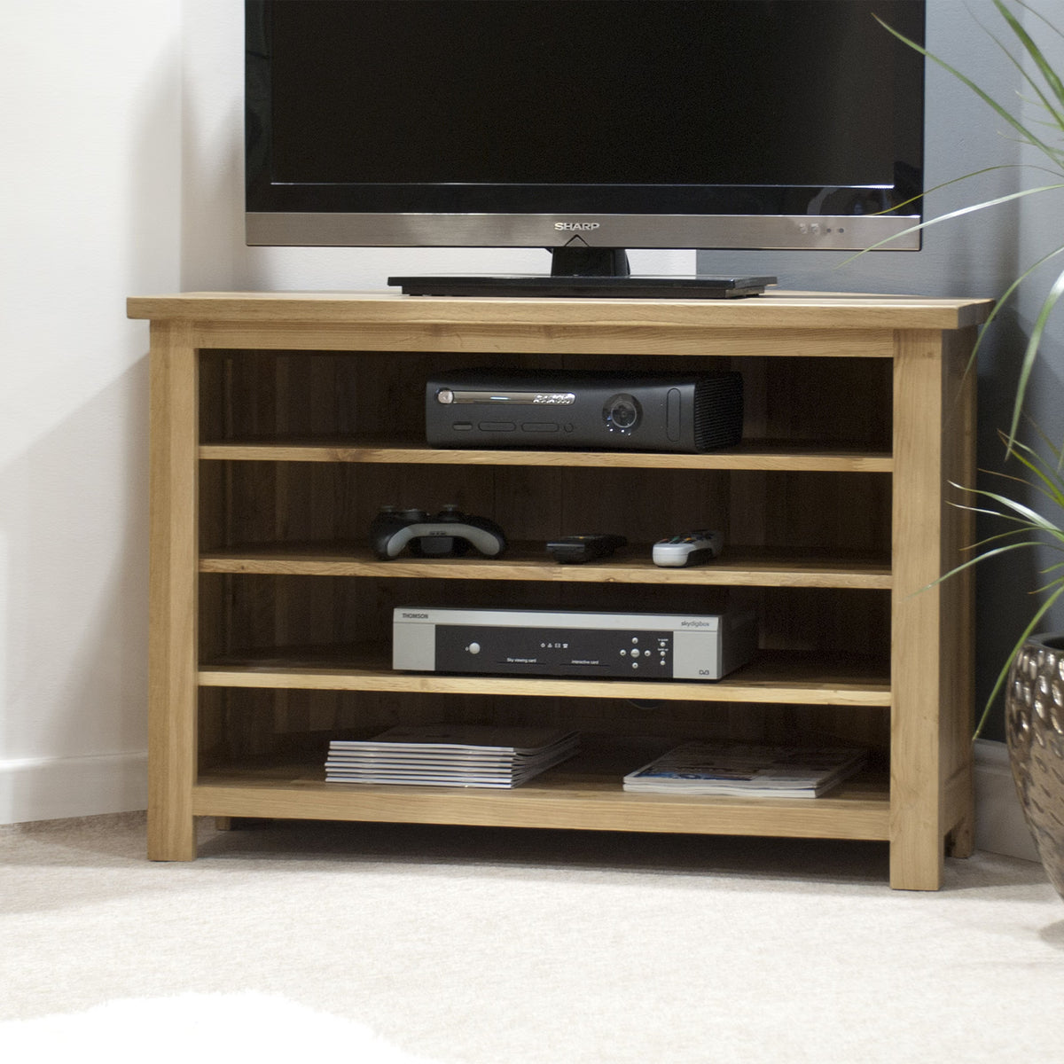 Oak TV unit with open shelves, holding electronics and game controllers in living room corner