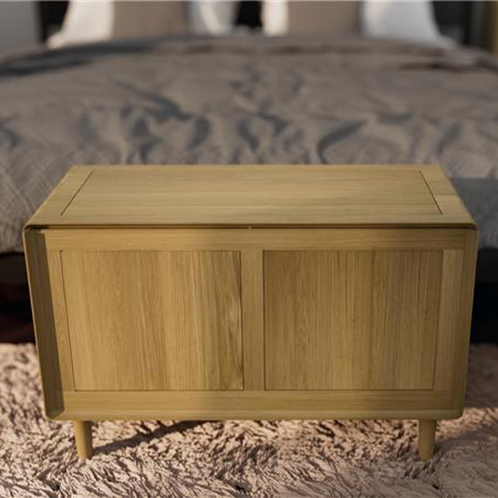 Oak storage bench with panelled design at the foot of a bed on a textured rug