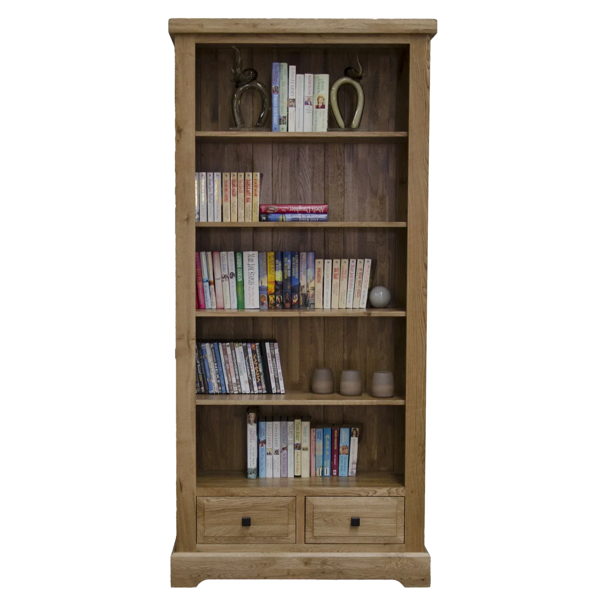Tall oak bookcase with four shelves, books, ornaments, and two lower storage drawers
