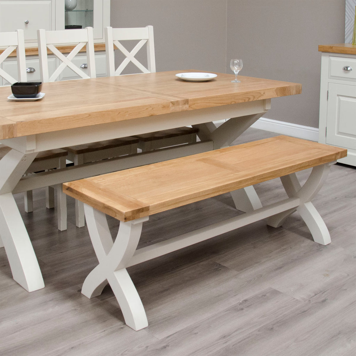 Oak dining table with matching bench and cross-back chairs in modern dining room