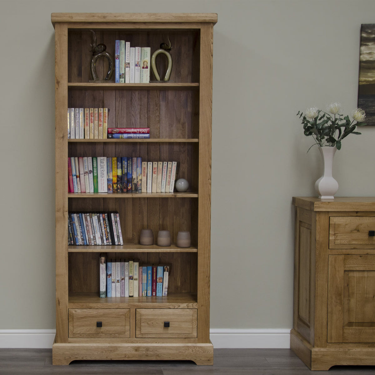 Tall oak bookcase with shelves and two drawers, styled with books and ornaments