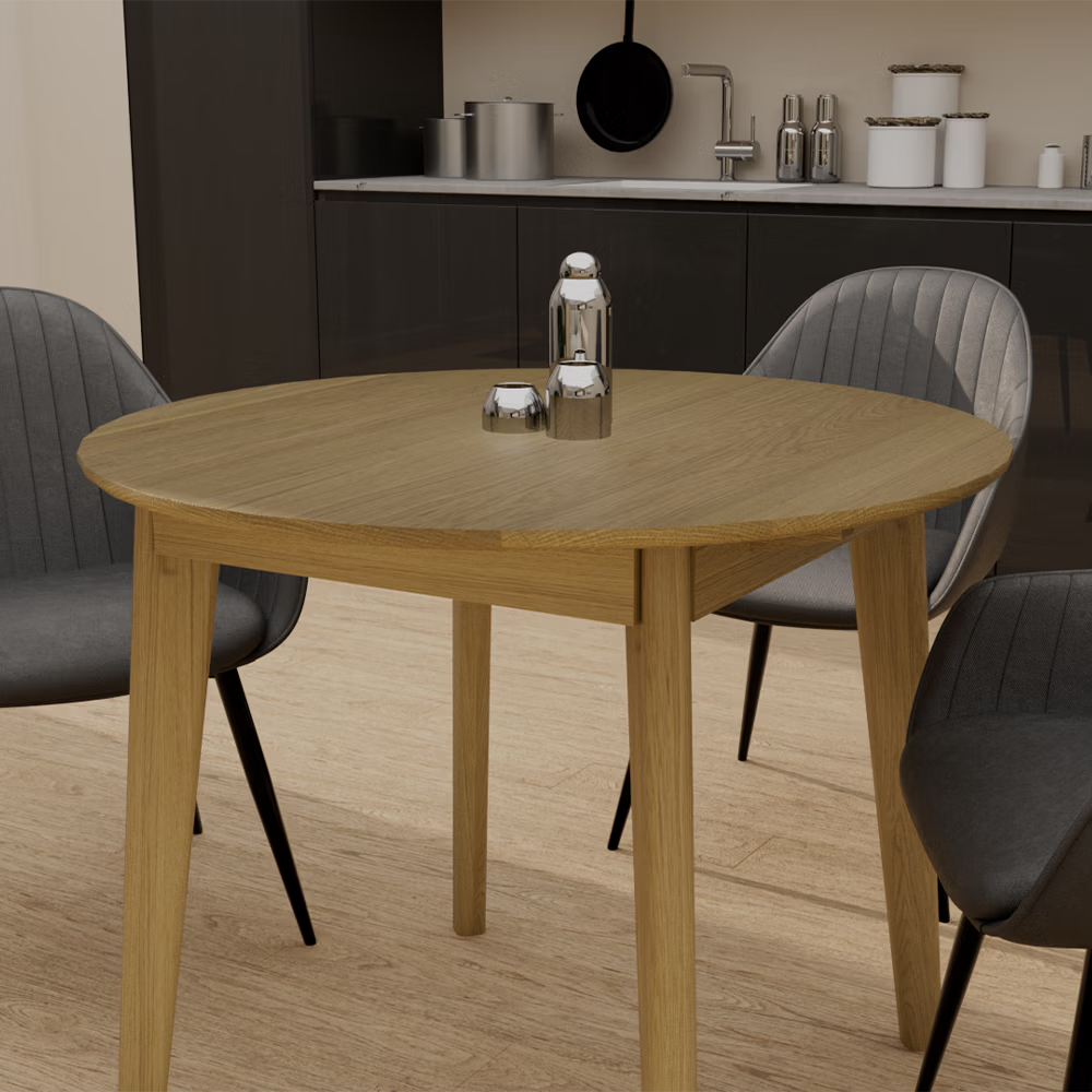 Round oak dining table with grey upholstered chairs in modern kitchen setting