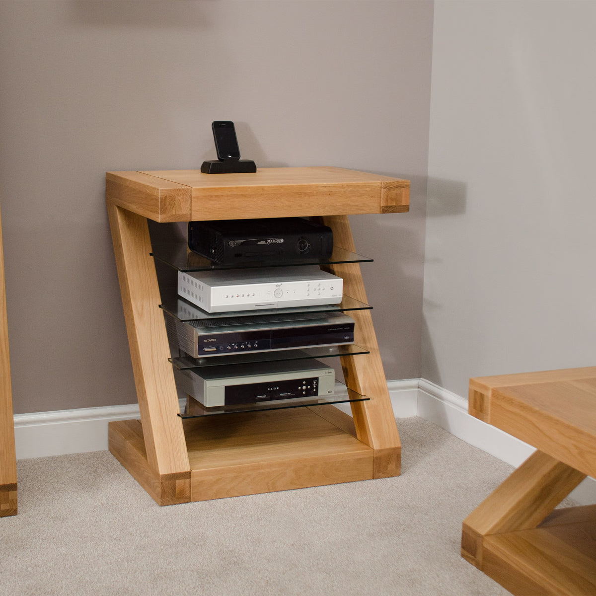 Oak media unit with glass shelves holding electronics in modern living room corner