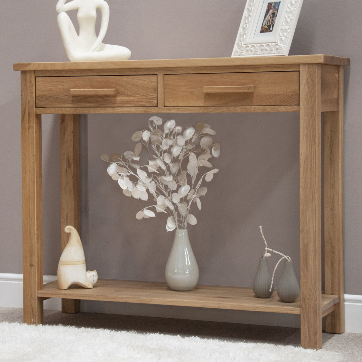 Oak console table with two drawers, lower shelf, ceramic vase and decorative ornaments