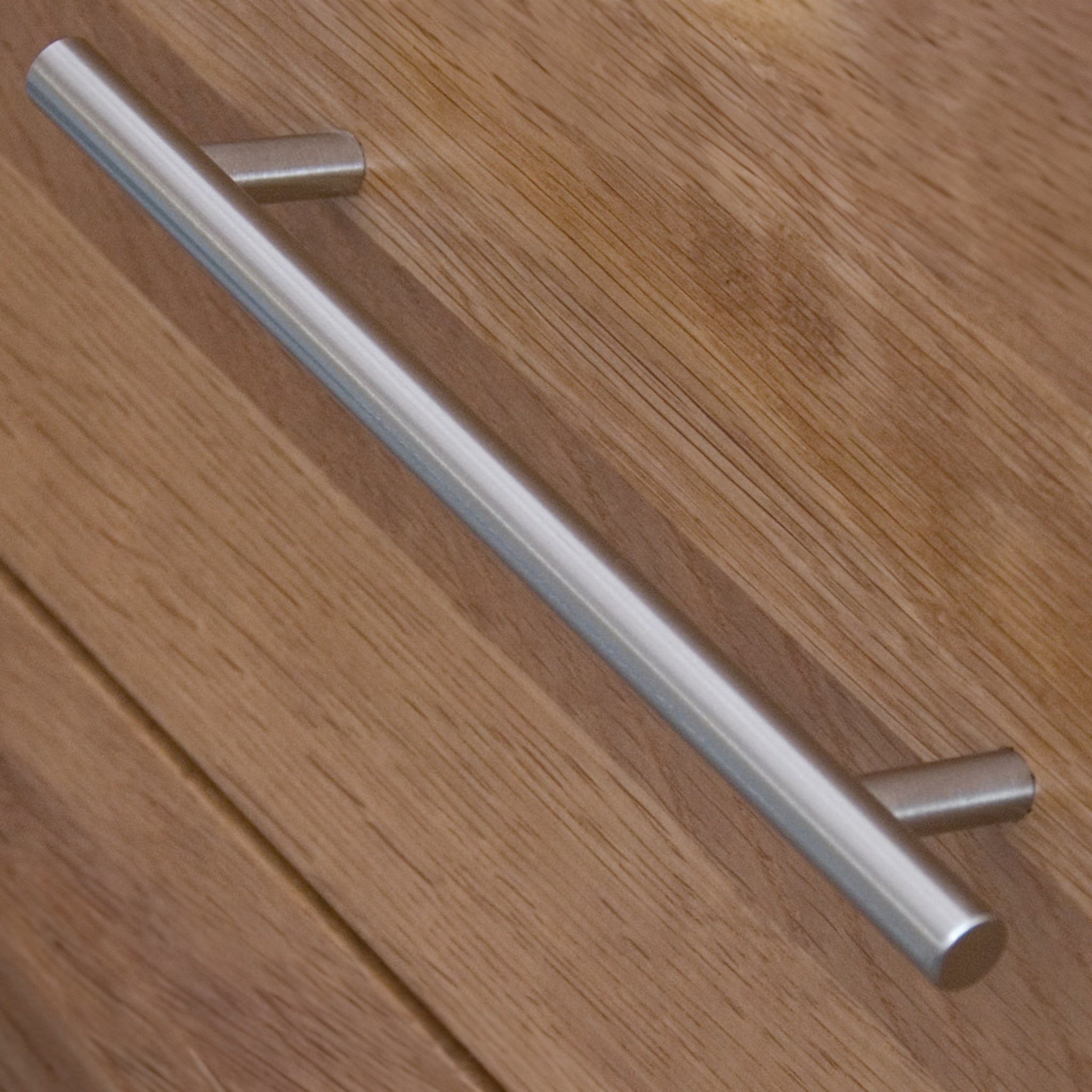 Metal drawer handle on oak wood cabinet close up