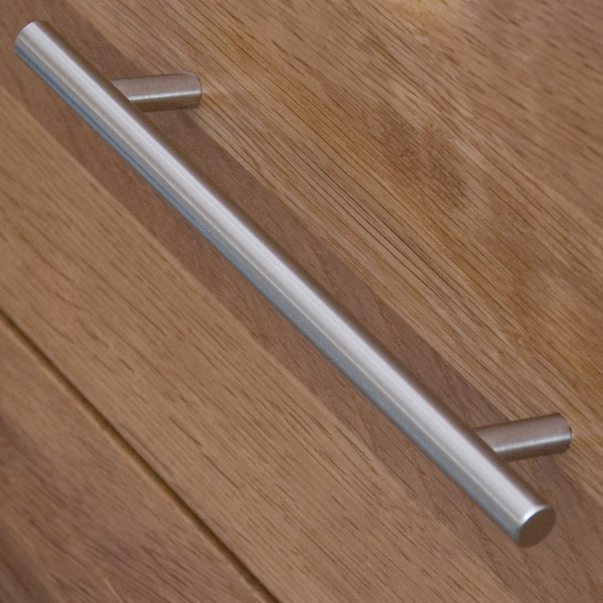 Metal drawer handle on oak wood cabinet close up