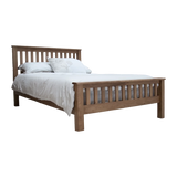 Oak wooden bed frame with slatted headboard and white bedding, side angle view