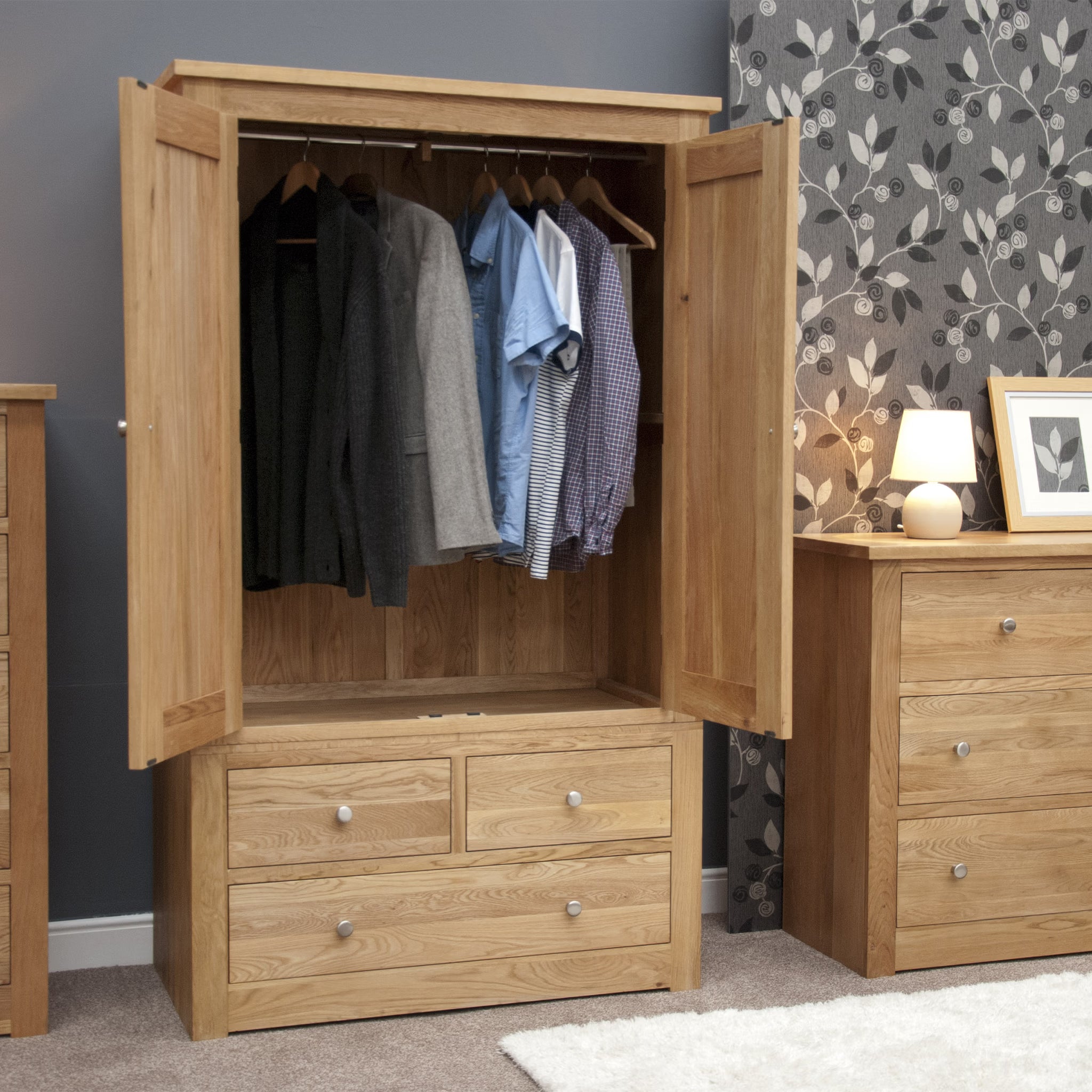 Oak wardrobe with hanging rail, two doors open and three lower drawers in bedroom