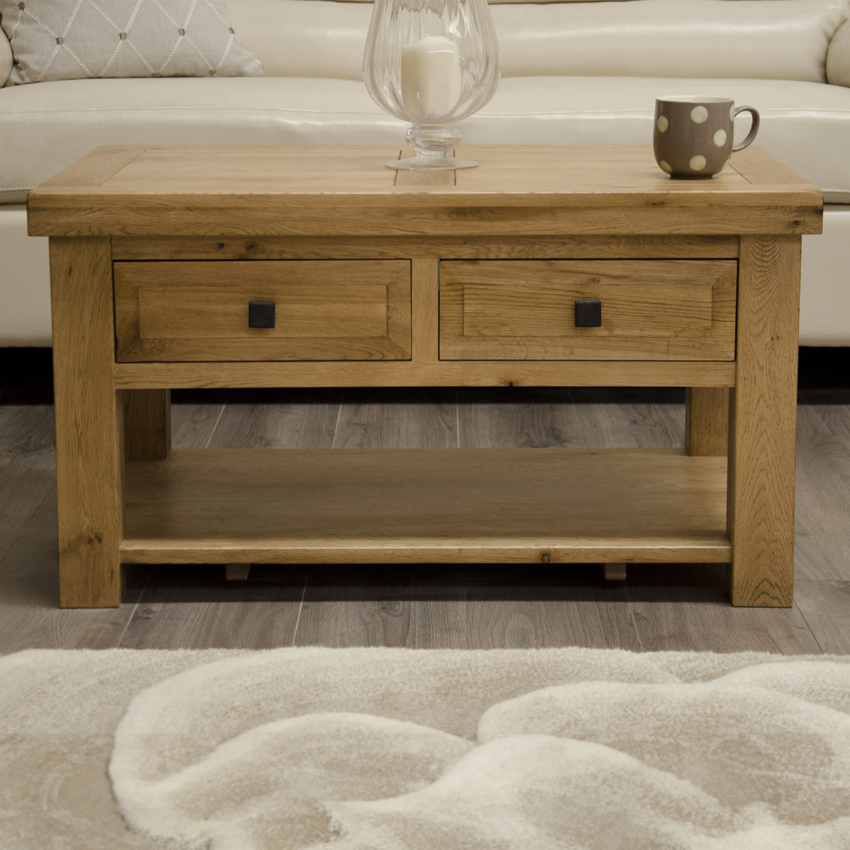 Oak coffee table with two drawers and lower shelf, placed on wood floor near sofa