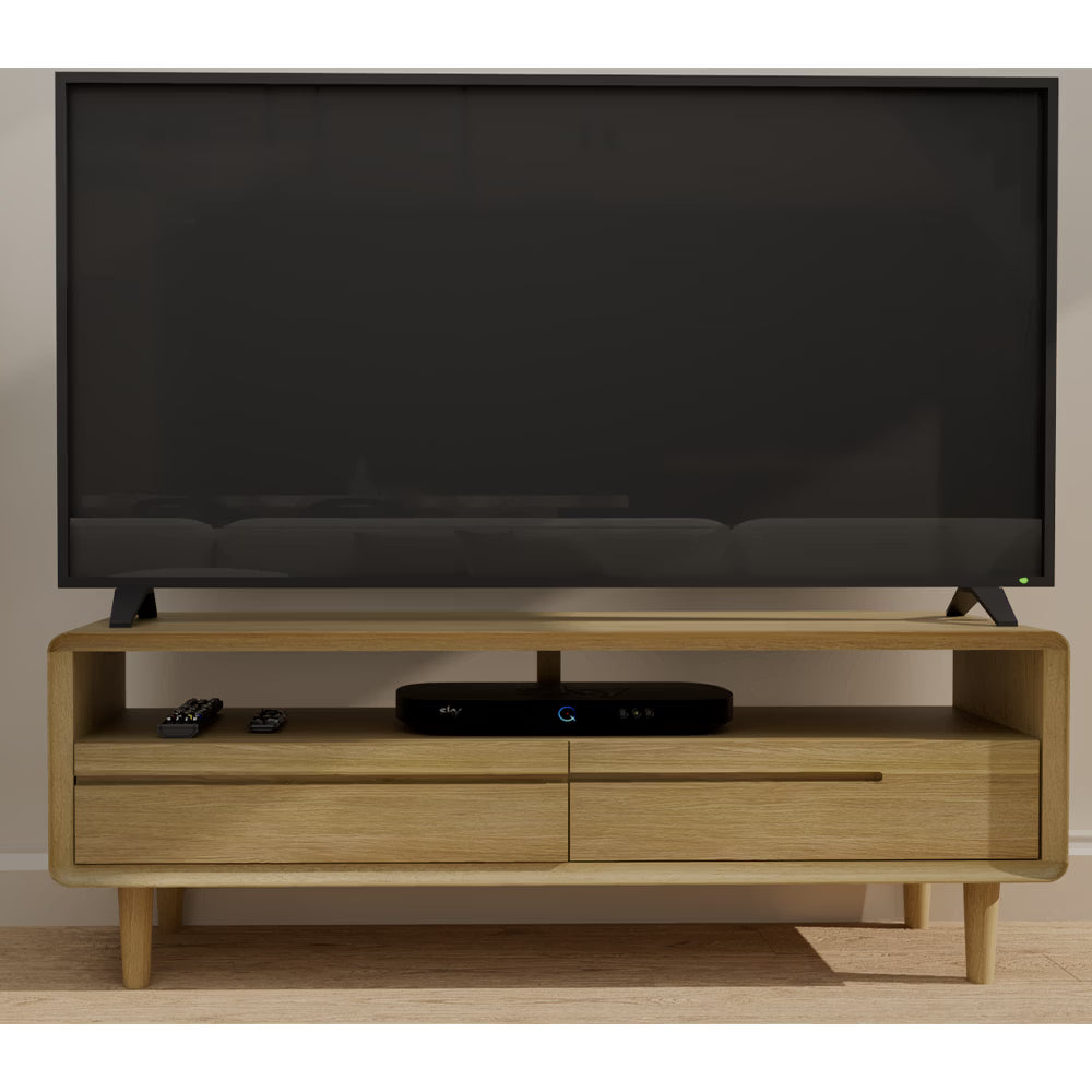 Oak TV unit with open shelf, two drawers, and media devices on wood floor