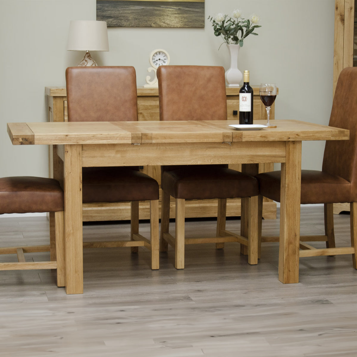 Oak dining table with four brown leather chairs in modern dining room setting